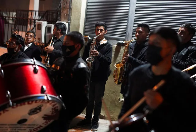 A band performs as people mourn a victim of a landslide after torrential rains sent mud and rocks down on residences and affected electricity provision, in Quito, Ecuador, February 2, 2022. (Photo by Johanna Alarcon/Reuters)