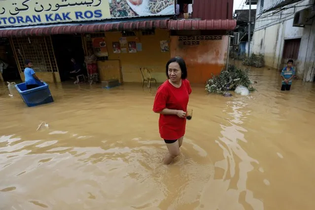 A woman holds her coffee cup as she walks through a flooded street on the outskirt of Kota Bharu in Kelantan December 29, 2014. (Photo by Athit Perawongmetha/Reuters)