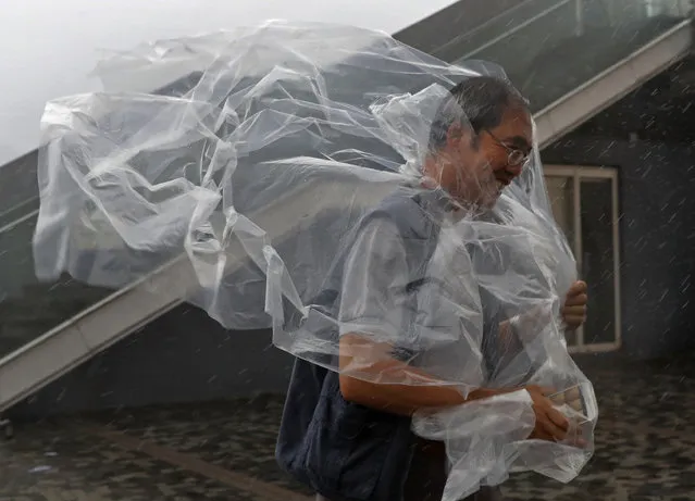 A man braves the wind on the waterfront of Victoria Habour as Typhoon Haima approaches Hong Kong, Friday, October 21, 2016. Typhoon Haima churned toward southern China on Friday after smashing into the northern Philippines with ferocious wind and rain, triggering flooding, landslides and power outages. (Photo by Vincent Yu/AP Photo)