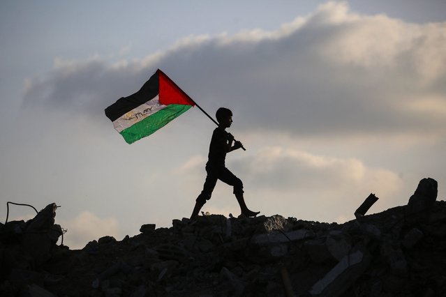 A displaced Palestinian child waves a Palestinian national flag as he walks on the rubble of a destroyed building at the Bureij camp for refugees in the central Gaza Strip on September 22, 2025. Britain, Australia, Canada and Portugal recognised the State of Palestine on September 21, a historic shift in decades of Western foreign policy that drew swift anger from Israel and a rebuke from the United States. (Photo by Eyad Baba/AFP Photo)