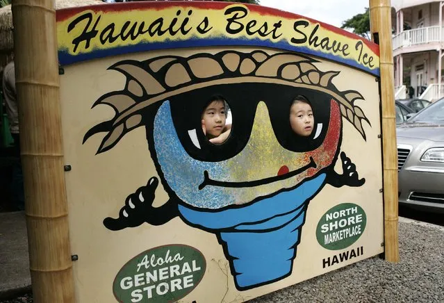 Japanese tourist kids get their picture taken at a “Shave Ice” stand on the North Shore in Haleiwa near where U.S. President Barack Obama and family were visiting a friend, Bobby Titcomb's house, for a luau during Obama's Christmas holiday vacation in Haleiwa, Hawaii, December 30, 2014. (Photo by Hugh Gentry/Reuters)