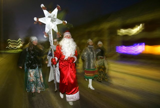 Belarusians celebrate “Kolyadki” in the village of Usyazh, some 40 km (25 miles) north-east of Minsk, Belarus, Tuesday, January 6, 2015. Kolyadki is a pagan winter holiday, which has over the centuries merged with Orthodox Christmas celebrations. Fancy-dressed people go from house to house, singing, dancing, eating and drinking. The hosts give money or food to their guests. (Photo by Sergei Grits/AP Photo)