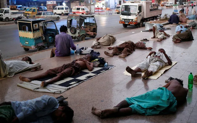 Residents sleep on a pavement to escape heat and frequent power outages in their residential area in Karachi, Pakistan on May 22, 2018. At least 65 people died due to heatstroke in the past three days in different parts of Pakistan' s southern port city of Karachi, where temperature hit 44 degrees Celsius. (Photo by Akhtar Soomro/Reuters)