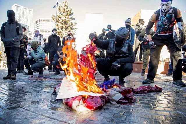 An Anti-Fascist Collation member is seen near a burning American flag after the inauguration of U.S. President Joe Biden, in Denver, Colorado, U.S. January 20, 2021. (Photo by Alyson McClaran/Reuters)