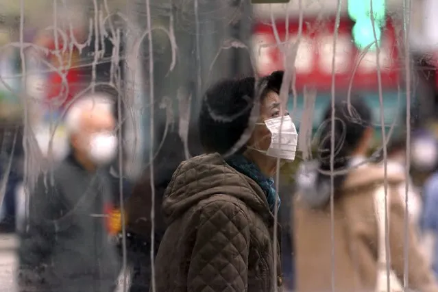 A woman wearing a protective mask to help curb the spread of the coronavirus stands is seen though a scribbled glass window as she walks along pedestrian crossings in the Shibuya area of Tokyo Tuesday, January 5, 2021. Japanese Prime Minister Yoshihide Suga says vaccine approval is being speeded up to curb the spread of the coronavirus, and he promised to consider declaring a state of emergency. The Japanese capital confirmed more than 1200 new coronavirus cases on Tuesday. (Photo by Eugene Hoshiko/AP Photo)