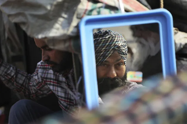 A Sikh farmer combs his beard at his makeshift tent at Singhu, Delhi-Haryana border camp for farmers protesting against three farm bills, in New Delhi, India, Wednesday, January 27, 2021. Leaders of a protest movement sought Wednesday to distance themselves from a day of violence when thousands of farmers stormed India's historic Red Fort, the most dramatic moment in two months of demonstrations that have grown into a major challenge of Prime Minister Narendra Modi's government. (Photo by Manish Swarup/AP Photo)