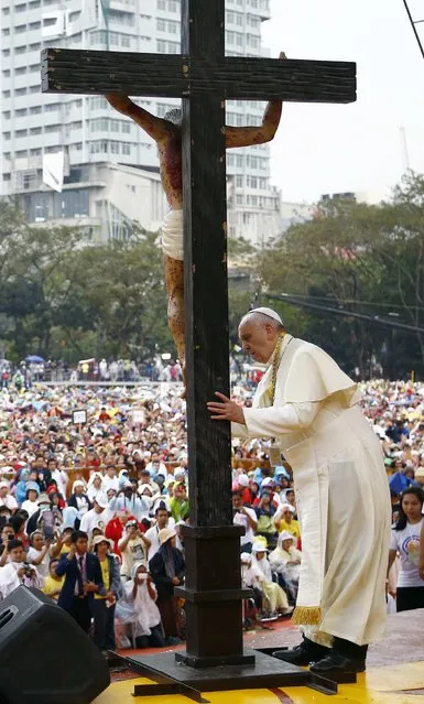 Pope Francis touches a crucifix during a meeting with young people at Manila university, January 18, 2015. (Photo by Stefano Rellandini/Reuters)