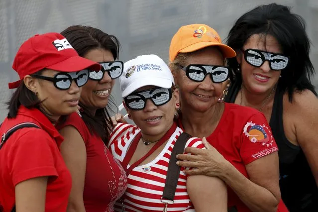 Supporters of Venezuela's President Nicolas Maduro wearing glasses depicting the eyes of late Venezuelan President Hugo Chavez pose for a picture during the last campaign rally with pro-government candidates for the upcoming parliamentary elections, in Caracas December 3, 2015. (Photo by Carlos Garcia Rawlins/Reuters)