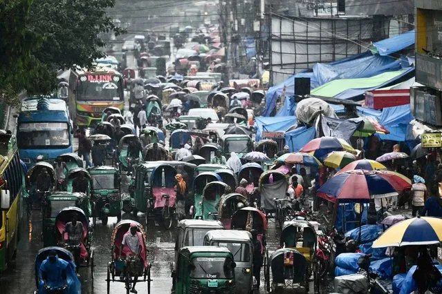 Vehicles make their way along a busy road during a rainfall in Dhaka on June 9, 2023. (Photo by Munir Uz Zaman/AFP Photo)