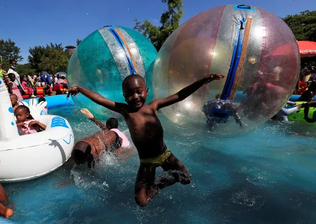 A child jumps in the portable swimming pool at the Uhuru Park grounds for Christmas Day celebrations in Nairobi, Kenya on December 25, 2020. (Photo by Thomas Mukoya/Reuters)