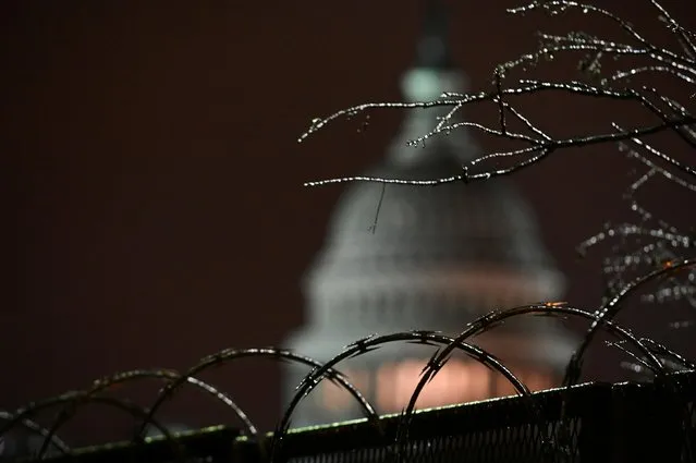 The U.S. Capitol is seen through ice-covered tree branches above barbed wire on a security fence after the Senate voted to acquit former U.S. President Donald Trump during his impeachment trial, in Washington, U.S. February 13, 2021. (Photo by Erin Scott/Reuters)