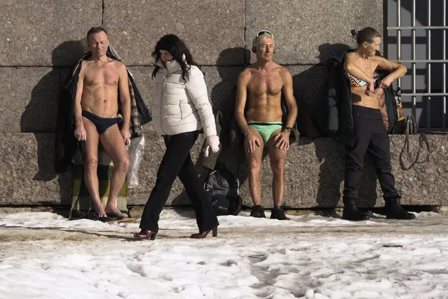 People stand in the sun against the wall of Peter and Paul fortress on the bank of the Neva River in St. Petersburg, Russia, Tuesday, March 2, 2021. The air in St. Petersburg warmed up to 4 degrees Centigrade (39 degrees Fahrenheit). (Photo by Dmitri Lovetsky/AP Photo)