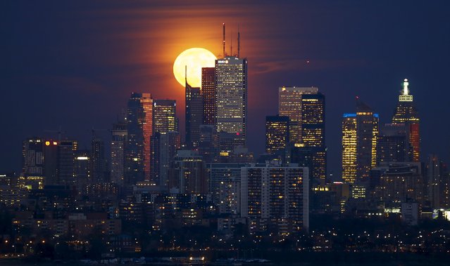 The moon rises behind the skyline and financial district in Toronto, November 25, 2015. (Photo by Mark Blinch/Reuters)
