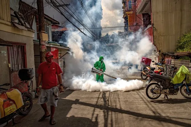 A worker wearing a hazmat suit uses a fogging machine to disinfect a street as preventive measure against COVID-19 on March 26, 2021 in Manila, Philippines. Curfews and stricter lockdowns are being implemented in several areas across the Philippines as the country experiences its worst surge in cases since the lockdown began more than a year ago. The country has reported more than 693,000 cases of COVID-19 so far, with at least 13,095 deaths. (Photo by Ezra Acayan/Getty Images)