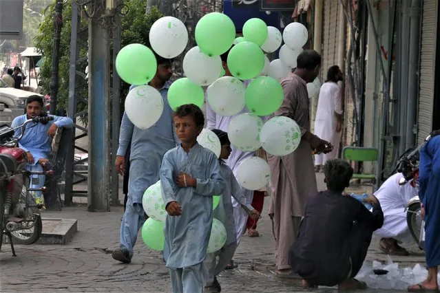 A vendor holds balloons of National flag color with letters reading “happy Independence Day” at a market in Peshawar, Pakistan, Monday, Aug. 14, 2023. Millions of Pakistanis celebrate the 76th Independence Day from British rule. (Photo by Muhammad Sajjad/AP Photo)