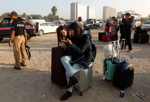 Foreign guests with their belongings wait outside after a fire erupted in a hotel early morning in Karachi, Pakistan, December 5, 2016. (Photo by Akhtar Soomro/Reuters)