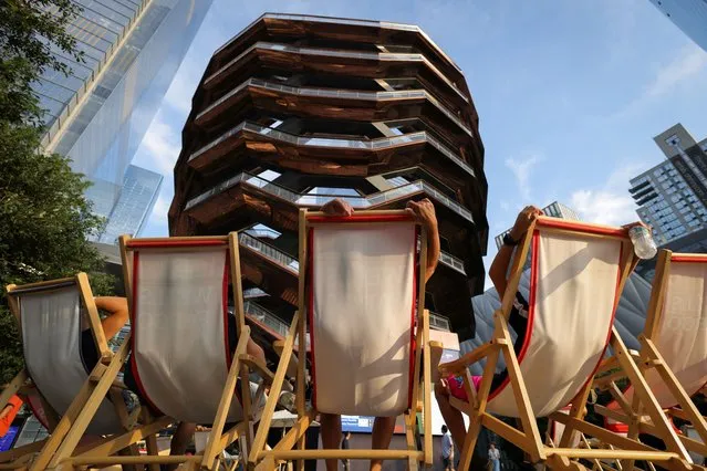 People sit in deckchairs by The Vessel in Hudson Yards as high temperatures hit the region in New York, U.S., September 5, 2023. (Photo by Andrew Kelly/Reuters)