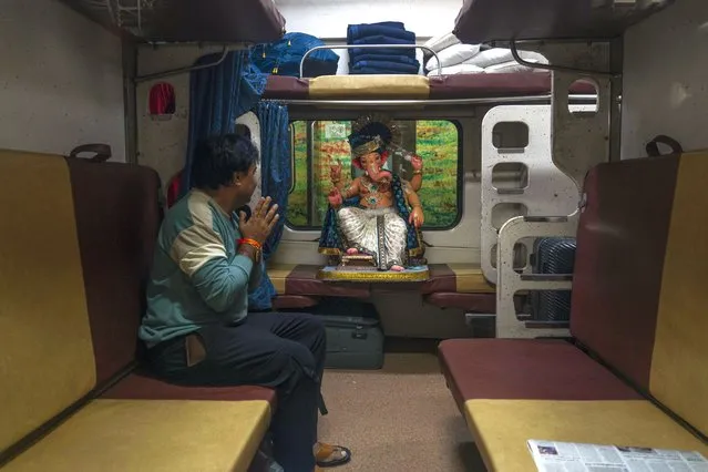A Hindu devotee gestures respectfully towards a clay idol of elephant headed Hindu god Ganesh as he transports the same in a passenger train for worship in Mumbai, India, India, Sunday, September 10, 2023. Devotees will conduct prayers during the 10-day-long Ganesh Chaturti festival, which will end with the immersion of the idols in different water bodies. (Photo by Rafiq Maqbool/AP Photo)