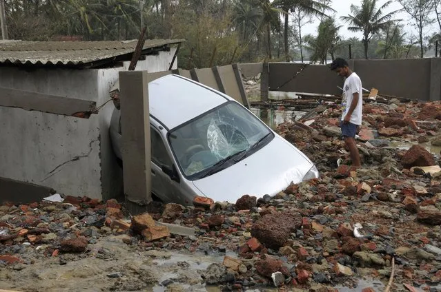 A man looks at a car damaged due to Cyclone Yaas that made a landfall Wednesday at Digha on the Bay of Bengal coast, West Bengal state, India, Thursday, May 27, 2021. (Photo by Ashim Paul/AP Photo)
