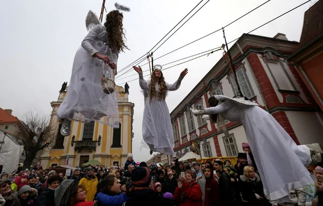 Women dressed as angels wave to spectators as they hang from a wire during a Christmas market in the town of Ustek, Czech Republic December 17, 2016. (Photo by David W. Cerny/Reuters)