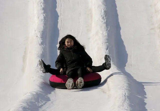 Girls on a tube rides a slide covered with snow during the Ice and Snow carnival at Taoranting park in Beijing, China, January 25, 2016. (Photo by Kim Kyung-Hoon/Reuters)