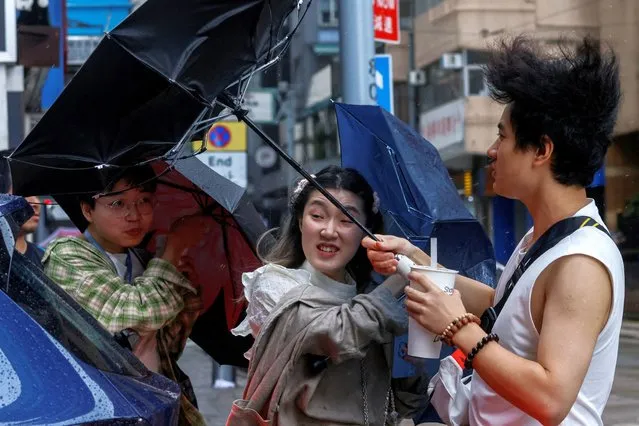 People struggle with umbrellas while walking against strong wind, as Typhoon Koinu approaches, in Hong Kong, China on October 8, 2023. (Photo by Tyrone Siu/Reuters)