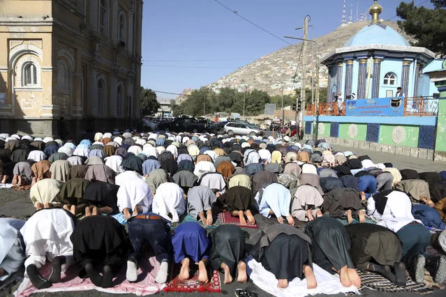 Men attend Eid al-Adha prayers outside of the Shah-e-Dushamshera mosque in Kabul, Afghanistan, Tuesday, August 21, 2018. During the Eid al-Adha, or Feast of Sacrifice, Muslims slaughter sheep or cattle and distribute portions of the meat to the poor. (Photo by Rahmat Gul/AP Photo)