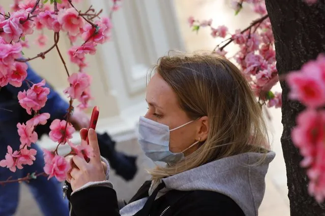 A woman wearing a face mask to help curb the spread of the coronavirus takes photo of fake flowers at the GUM, the State Department store, near Red Square in Moscow, Russia, Thursday, June 10, 2021. The Russian authorities reported a spike in coronavirus infections on Thursday, with new confirmed cases exceeding 11,000 for the first time since March. (Photo by Alexander Zemlianichenko/AP Photo)