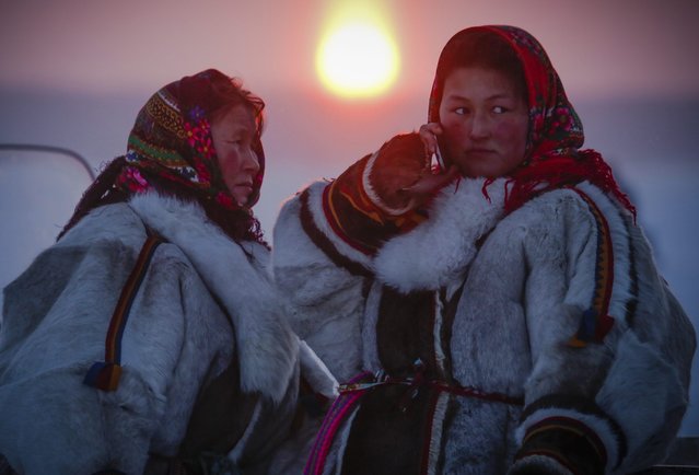 In this photo taken on Sunday, March 15, 2015, Nenets women speak at sunset after the Reindeer Herder's Day holiday in the city of Nadym, in Yamal-Nenets Region, 2500 kilometers (about 1553 miles) northeast of Moscow, Russia. For the indigenous nomadic Nenets people, the Reindeer Herder’s Day offers a chance to show their prowess in wrestling, high jumps and other traditional local sports, but, above all, reindeer races. (Photo by Dmitry Lovetsky/AP Photo)