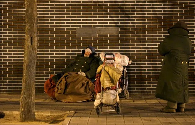 Homeless people are seen on a cold winter night near Beijing South Railway Station in Beijing, China, January 23, 2016. According to Xinhua News Agency, China's national observatory raised the weather warning alert to orange on Saturday morning as much of the country braced for the worst cold in 30 years. (Photo by Jason Lee/Reuters)