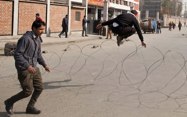 A Kashmiri Shiite Muslim jumps over a barbed wire to evade arrest after they were stopped by security forces during a Muharram procession in Srinagar, India, Wednesday, November 13, 2013. (Photo by Dar Yasin/AP Photo)