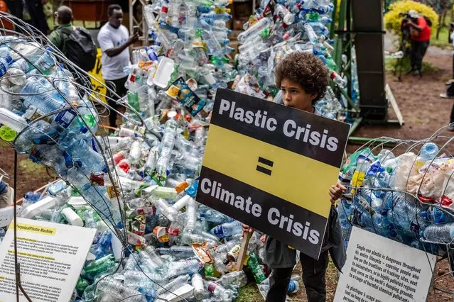 A young climate activist holds a banner in front of a plastic installation after marching to demand drastic reduction in global plastic production during the Break Free From Plastic Movement March ahead of the third meeting of the Intergovernmental Negotiating Committee (INC-3) in Nairobi on November 11, 2023. The third session of the Intergovernmental Negotiating Committee (INC-3) is scheduled to take place from November 13, 2023 in Nairobi and aims to develop an international legally binding instrument on plastic pollution. (Photo by Luis Tato/AFP Photo)