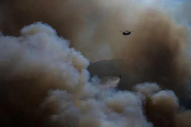 A helicopter participates in a wildfire extinguishing operation, in Koycegiz, Mugla, Turkey, Monday, August 9, 2021. Wildfires in Turkey, described as Turkey's worst in living memory, started on July 28 amid a ferocious heatwave and raged on for days across more than half of Turkey's provinces. At least eight people and countless animals have been killed and villages and resorts had to be evacuated, with some people fleeing to beaches to be rescued by sea. (Photo by Emre Tazegul/AP Photo)
