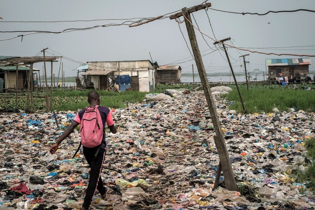 A man walks on plastic waste, used to reclaim a swamp so that the land can be developed for housing, in the Mosafejo area of Lagos on February 12, 2019. Nigeria, which elects a new president on February 16, is Africa's most populous nation and leading oil producer but is dogged by poverty and insecurity. (Photo by Yasuyoshi Chiba/AFP Photo)