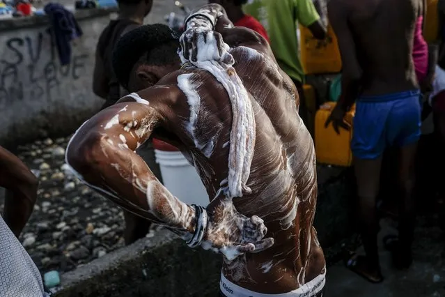 A man bathes outdoors due to no running water at his home in Les Cayes, Haiti, Friday, August 20, 2021, six days after a 7.2 magnitude earthquake hit the area. (Photo by Matias Delacroix/AP Photo)