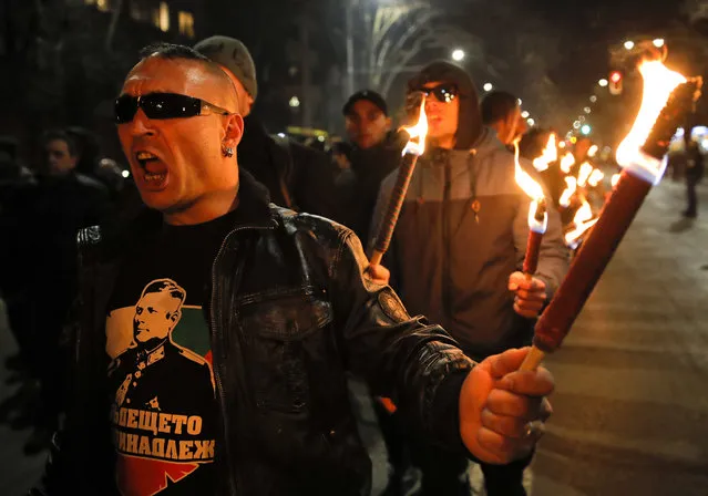 A man holds a flare chanting the name of Gen. Hristo Lukov, who had supported Germany during the Second World War, depicted on his t-shirt, as people take part in the “Lukov March”, staged by the far-right Bulgarian National Union, in Sofia, Bulgaria, Saturday, February 16, 2019. Bulgarian nationalists have marched through Sofia, the country's capital, to honor a World War II general known for his anti-Semitic and pro-Nazi activities. The annual Lukov March, staged by the far-right Bulgarian National Union, attracted hundreds of dark-clad supporters who walked through downtown Sofia holding torches and Bulgarian flags and chanting nationalist slogans. (Photo by Vadim Ghirda/AP Photo)