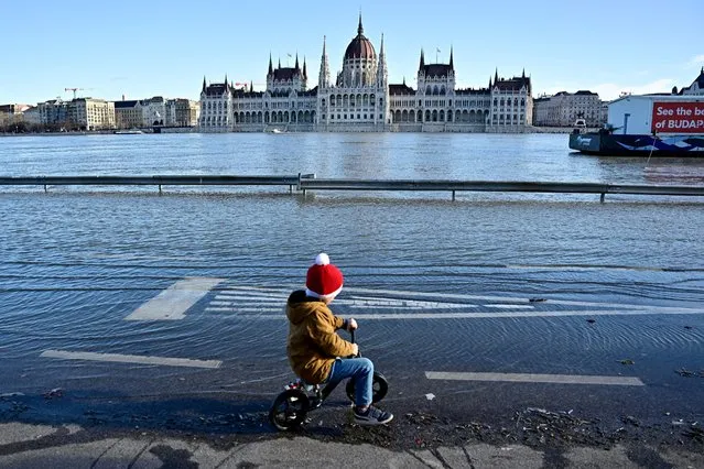 A child rides his bike on a quay flooded by the Danube River in Budapest, Hungary on December 27, 2023. (Photo by Marton Monus/Reuters)
