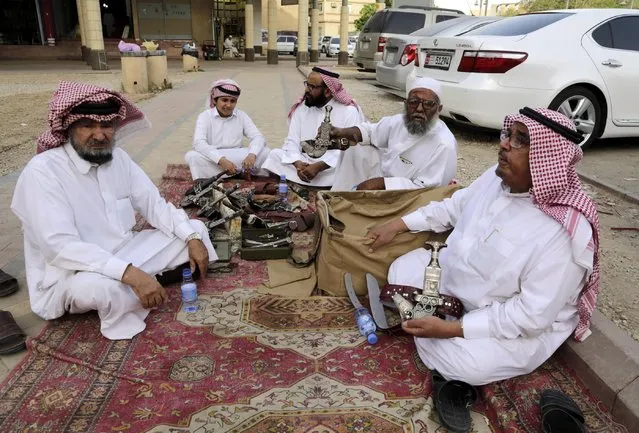 In this April 16, 2015 photo, dagger vendors sit together, one of them reciting poetry about traditional Saudi daggers, at al-Aqeeliya open-air auction market, in Riyadh, Saudi Arabia. Souvenir swords that sell as decorative pieces can go for more than 40 Saudi riyals ($10) in one of the market's stalls, but at the auction a whole bundle of 10 or more sells for 100 riyals ($27) to the highest bidder. (Photo by Hasan Jamali/AP Photo)