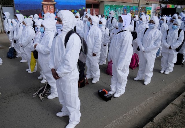 Healthcare workers, dressed in full protective gear, take part in a ceremony kicking off a door-to-door COVID-19 vaccination campaign, in El Alto, Bolivia, Thursday, September 16, 2021. The workers will return Friday, bringing vaccinations directly to people's homes. (Photo by Juan Karita/AP Photo)