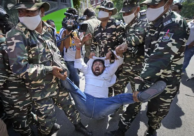 Paramilitary force soldiers detain an activist of Congress party's youth wing protesting against Sunday's killing of four farmers in Uttar Pradesh state after being run over by a car owned by India's junior home minister in New Delhi, India, Monday, October 4, 2021. Indian authorities on Monday suspended Internet services and barred political leaders from entering a northern town to calm tensions after eight people were killed in a deadly escalation of a year-long demonstration against contentious agriculture laws. (Photo by Manish Swarup/AP Photo)