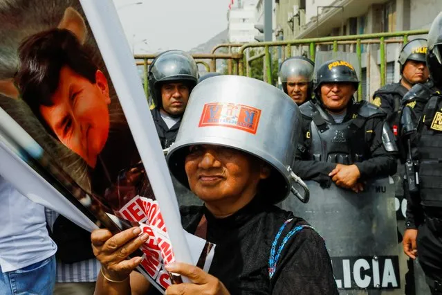 A demonstrator attends a protest while police officers stand guard after Congress approved the removal of President Pedro Castillo, in Lima, Peru on December 7, 2022. (Photo by Alessandro Cinque/Reuters)