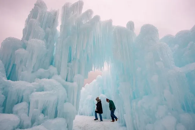 People explore the ice walls, trails and caverns at Ice Castles in North Woodstock, New Hampshire on February 1, 2024. Founder Brent Christensen, crafted his first icy creation in the front yard of his home to bring happiness and joy to his children. Since 2011, Ice Castles has been dedicated to creating a world of ice caves, frozen waterfalls, and glaciers formed into archways, caverns, slides, and tunnels. (Photo by Joseph Prezioso/AFP Photo)