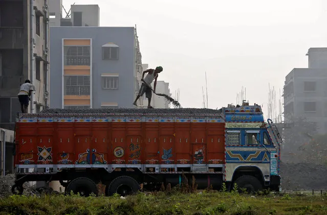 A labourer unloads construction material from a truck next to residential buildings under construction on the outskirts of Kolkata, India, February 1, 2017. (Photo by Rupak De Chowdhuri/Reuters)