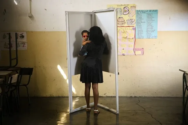 A Cape Verdean holds her child as she casts her vote during the legislative elections in Praia, Santiago Island, Cape Verde, 20 March 2016. About 350 thousand Cape Verdean voters are called to elect a new Government. (Photo by Mario Cruz/EPA)