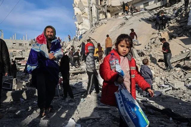 Palestinians walk away with some items salvaged from the rubble of a residential building hit in an overnight Israeli air strike in Rafah in the southern Gaza Strip on March 9, 2023, amid continuing battles between Israel and the Palestinian militant group Hamas. (Photo by Said Khatib/AFP Photo)