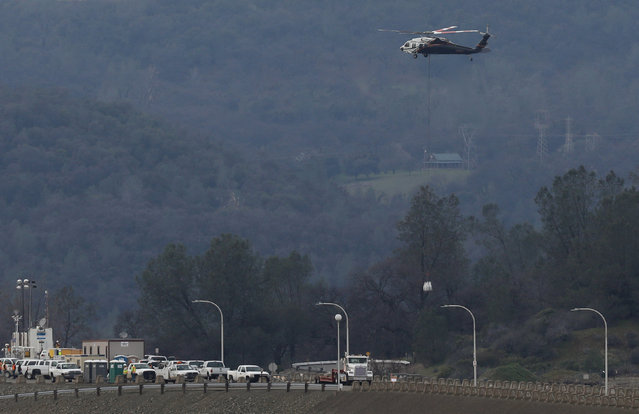 A helicopter prepares to drop rock at the Lake Oroville Dam after an evacuation was ordered for communities downstream from the dam in Oroville, California, U.S. February 13, 2017. (Photo by Jim Urquhart/Reuters)