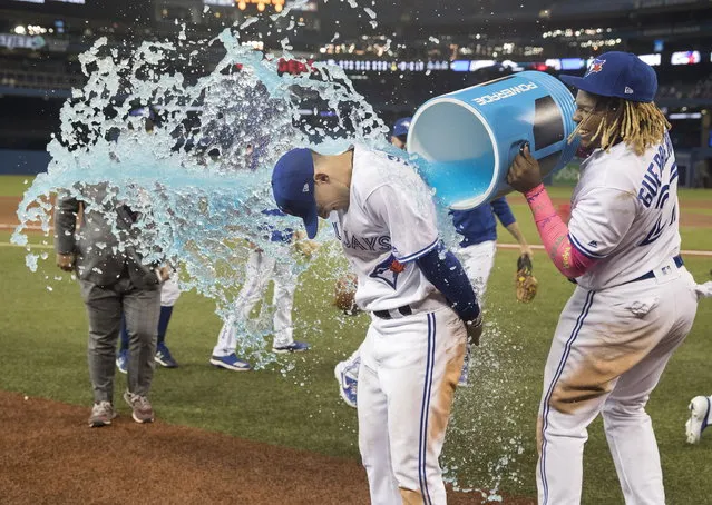 Toronto Blue Jays' Cavan Biggio gets a bucket shower from teammate Vladimir Guerrero Jr. during a post-game interview after the Jays defeated the San Diego Padres 10-1 in a baseball game in Toronto, Sunday, May 26, 2019. (Photo by Fred Thornhill/The Canadian Press via AP Photo)