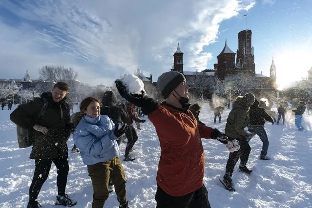 Snowballs fly during a snowball fight organized by the DC Snowball Fight Association, on the National Mall in the snow, Monday, January 3, 2022, in Washington. (Photo by Alex Brandon/AP Photo)