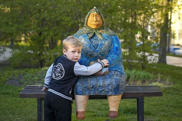 A child touches an artwork depicting a woman sitting on a bench in a park, in Kyiv, Ukraine, Tuesday, April 9, 2024. (Photo by Vadim Ghirda/AP Photo)