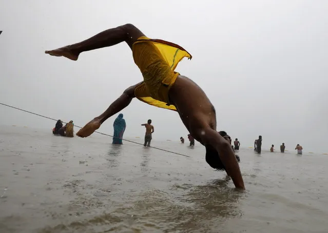 An Indian devotee performs yoga as he takes a holy dip at Sagar Island during second day of annual fair amid Covid crisis, 130km south of Kolkata, Eastern India, 14 January 2022. Bengal government announced a new partial lockdown and night curfew for fifteen days to combat new Omicron variant. Ganga Sagar Fair is an annual gathering of Hindu pilgrims during Makar Sankranti on Sagar Island, to take a dip in the sacred waters of the Ganges River before it reaches the Bay of Bengal. (Photo by Piyal Adhikary/EPA/EFE)
